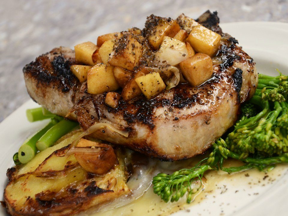 Concept photo: seared pork chop with caramelized apples and roasted potatoes